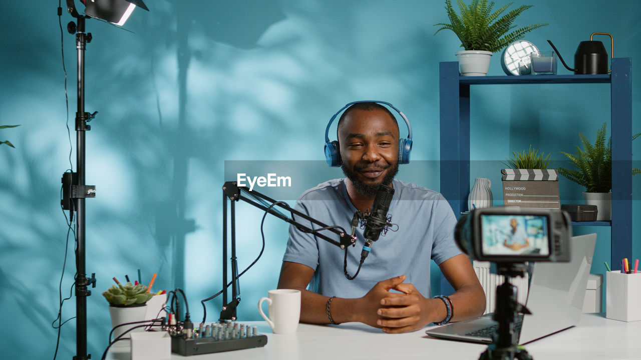 Happy man filming through camera at desk