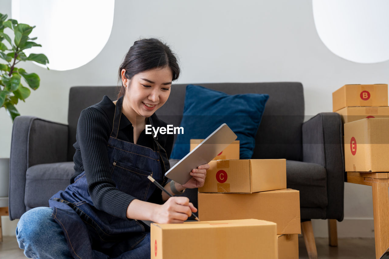 portrait of young woman using digital tablet while sitting on sofa at home