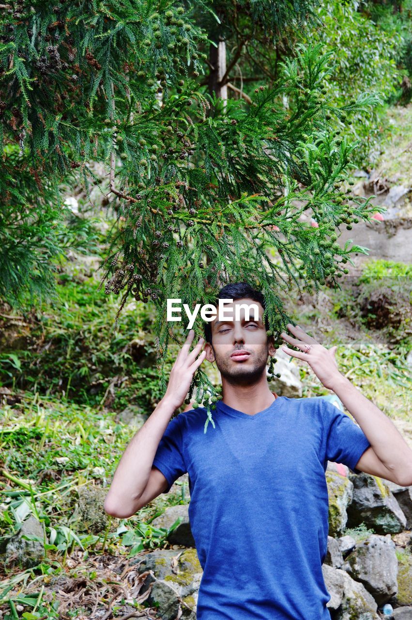 Young man standing against plants in forest