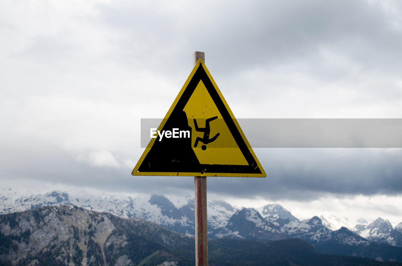 Warning sign on mountains against sky