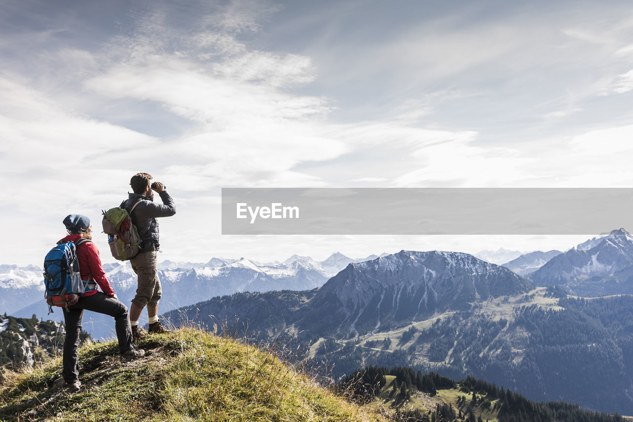 Austria, tyrol, young couple standing in mountainscape looking at view