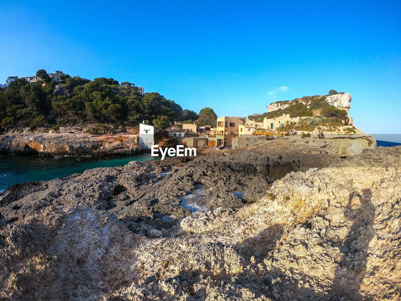 Rock formation amidst buildings against clear blue sky
