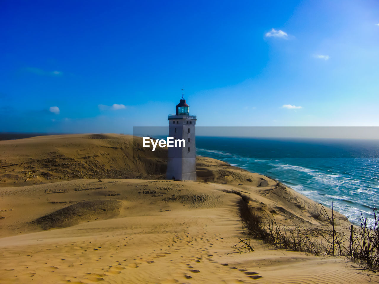 Lighthouse on beach by sea against sky