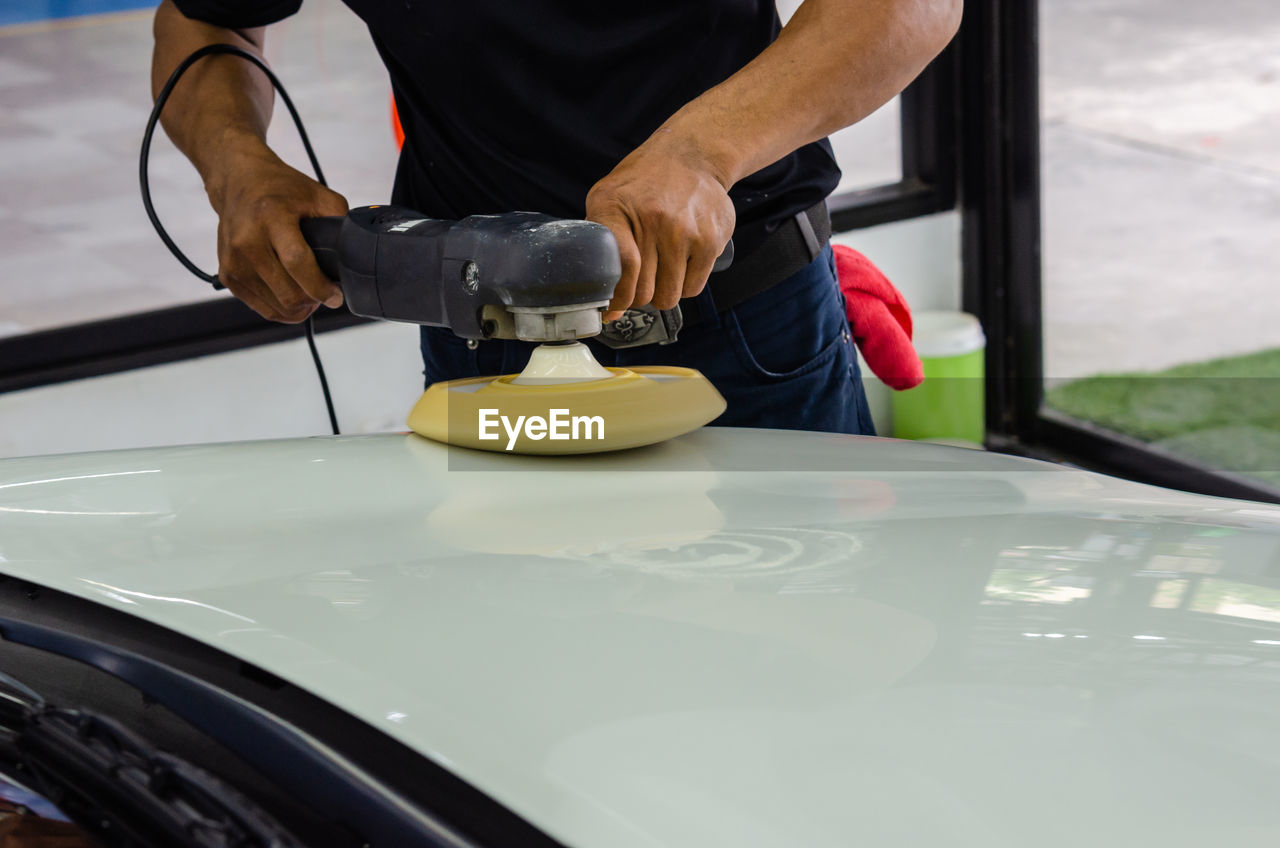 High angle view of man working with equipment on car in garage