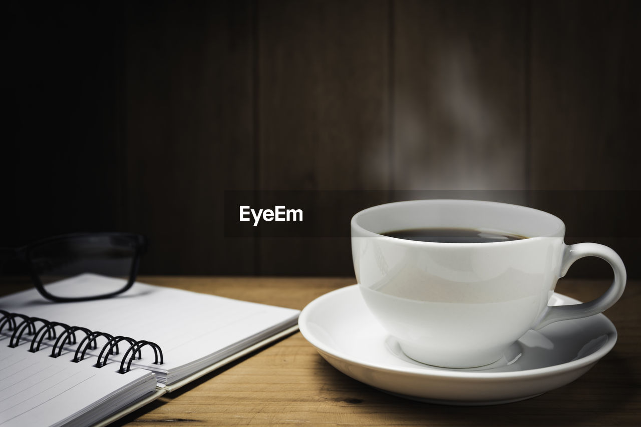 CLOSE-UP OF COFFEE CUP AND SPOON ON TABLE