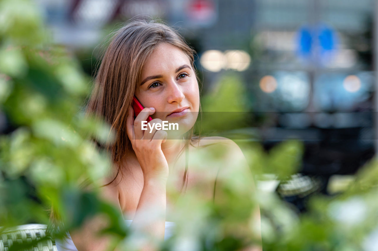 Young woman looking away while using phone outdoors