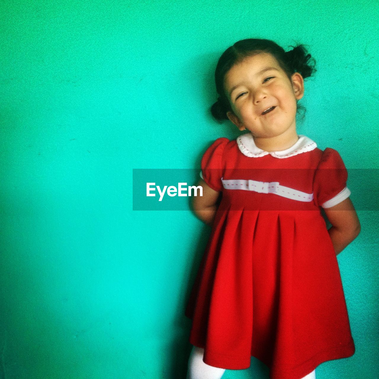 Portrait of cute girl standing against turquoise wall