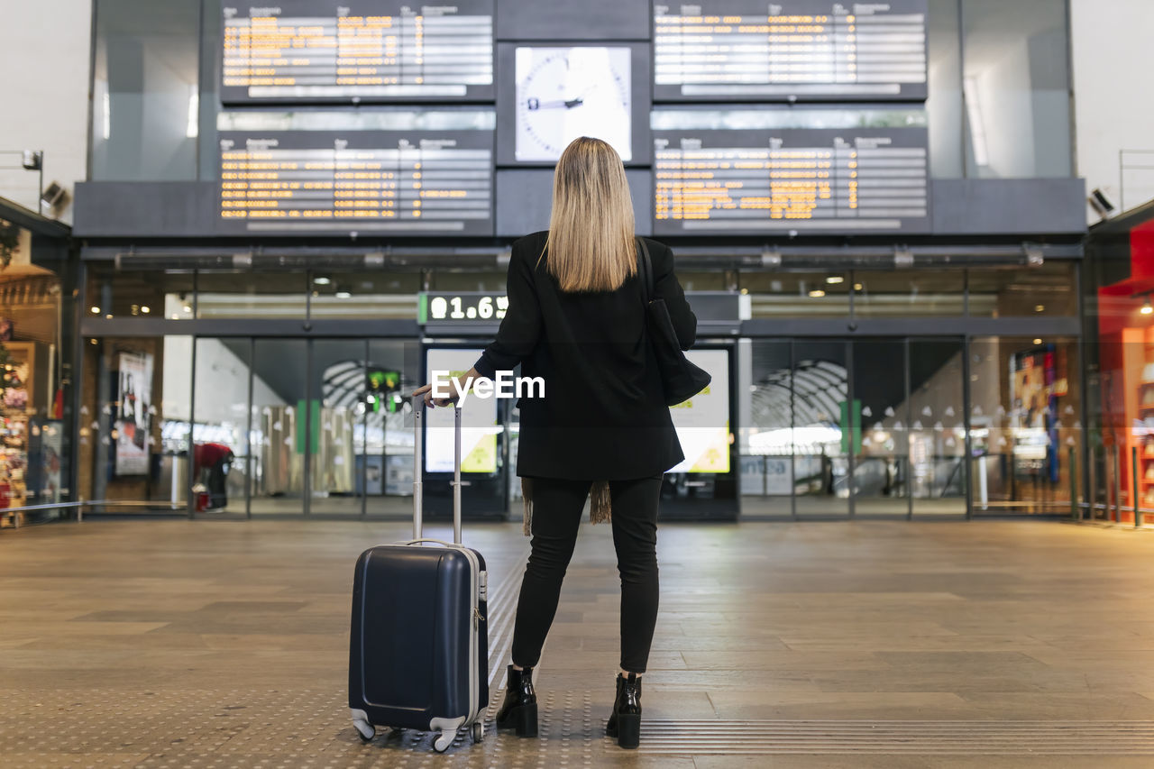 Woman looking at arrival departure board at railroad station