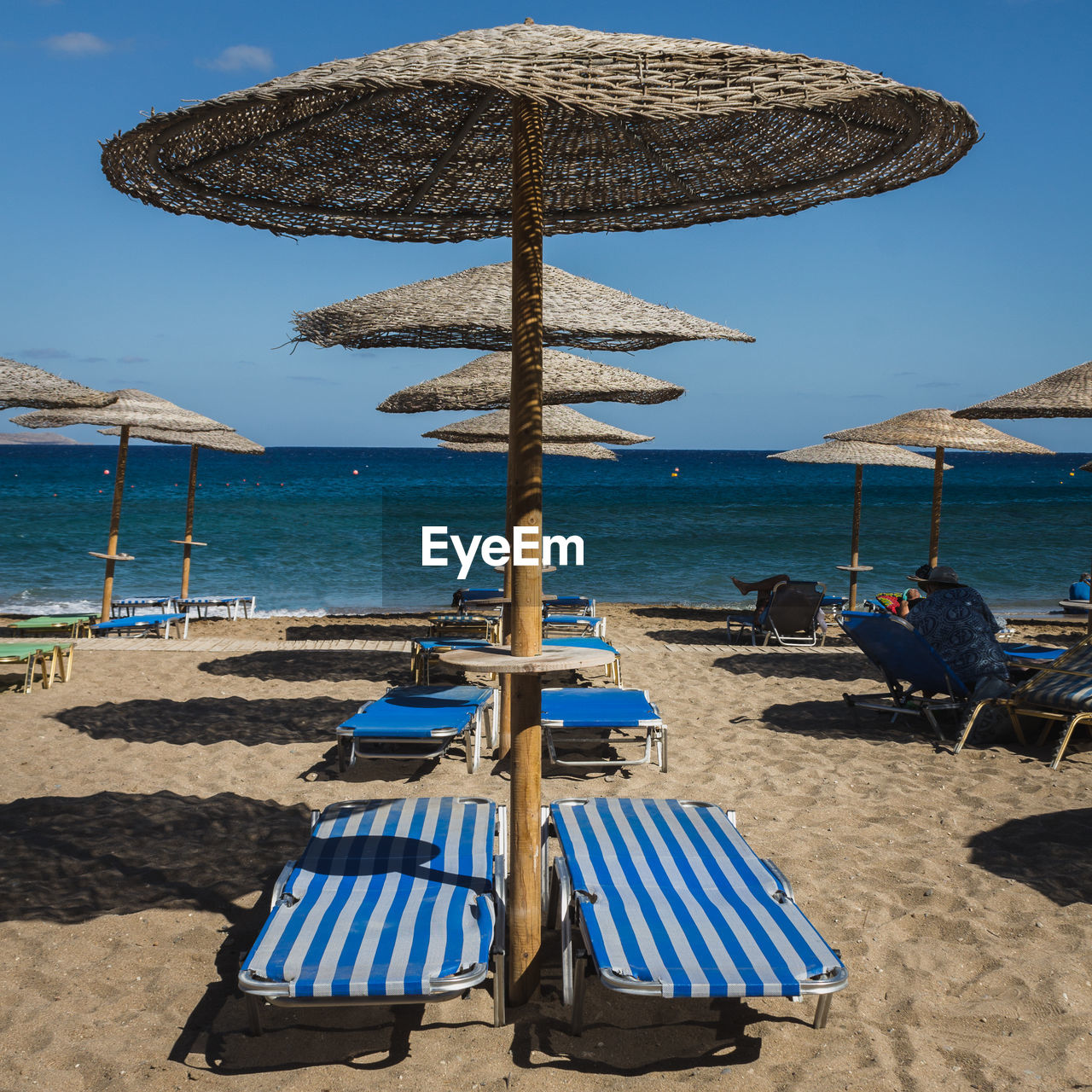 Deck chairs on beach against sky