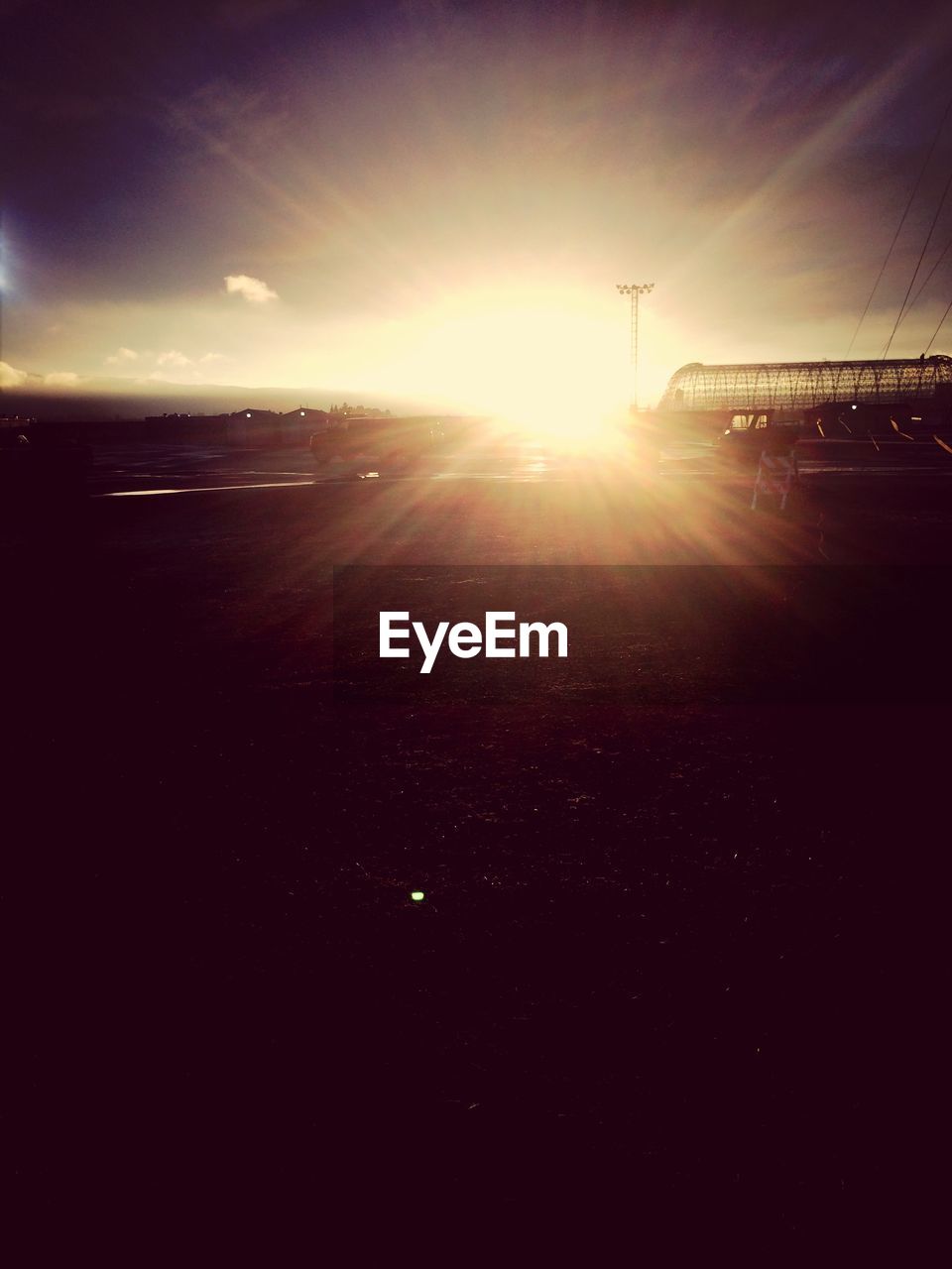 Sun shining on silhouette field against sky