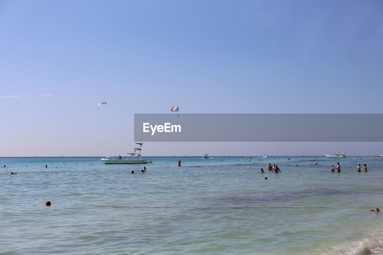 PEOPLE ON BEACH AGAINST CLEAR SKY