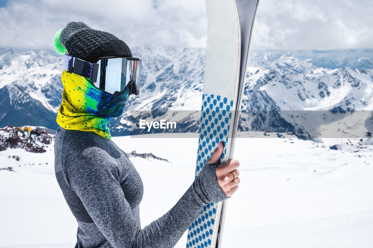 Portrait of a slender muslim sportswoman skier with a closed face with skis in her hands against 