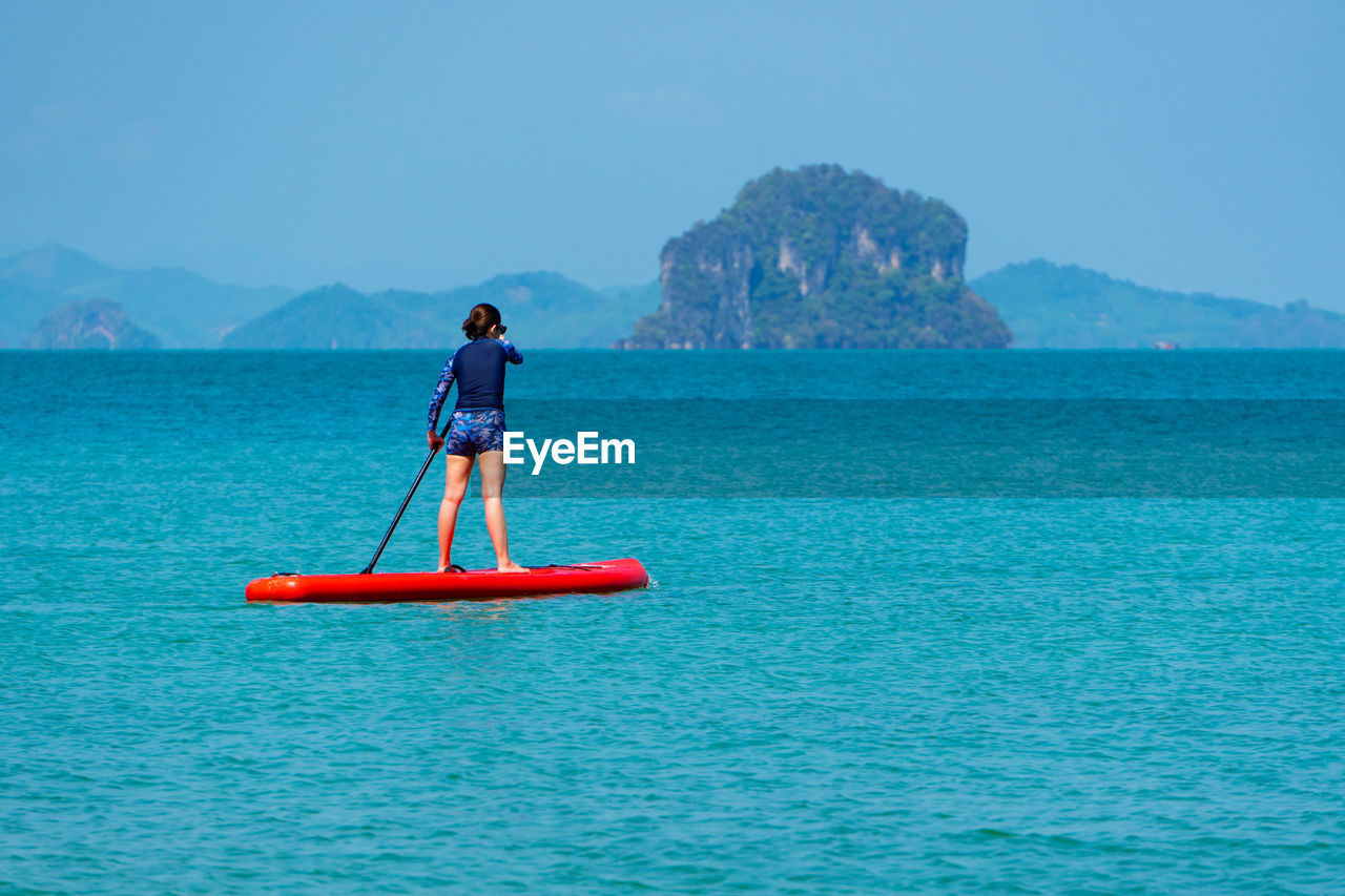 Man in sea against blue sky