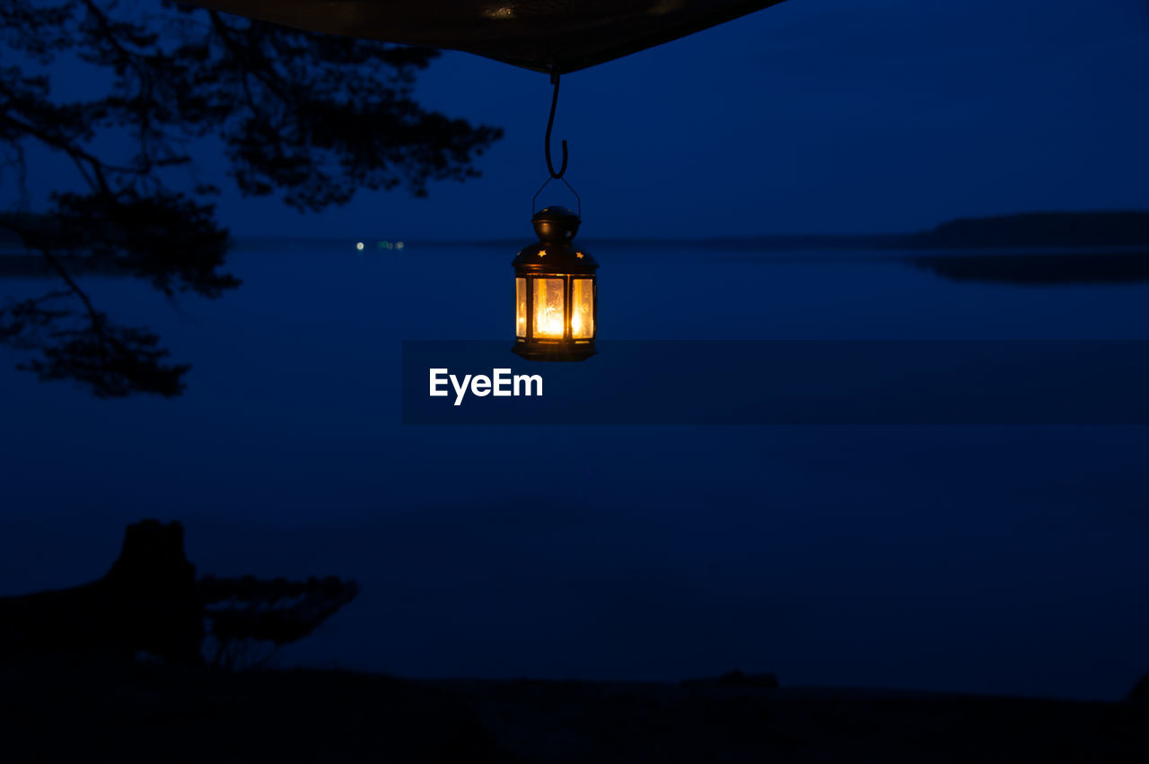 ILLUMINATED LAMP POST AGAINST SKY AT NIGHT