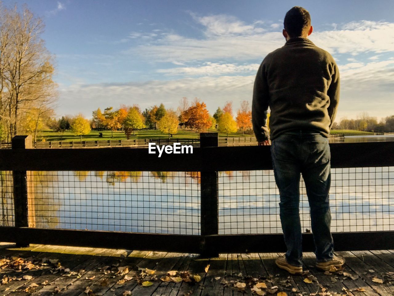 Rear view of man standing by bridge against sky