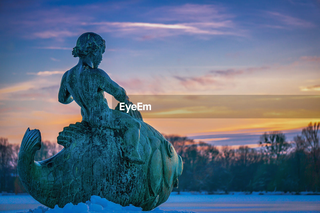 STATUE OF ANGEL DURING WINTER AGAINST SKY