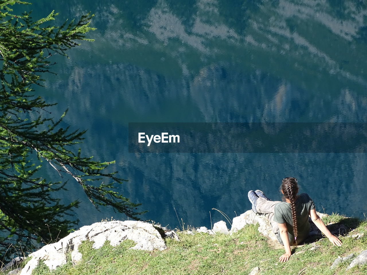 Rear view of woman sitting on mountain during sunny day