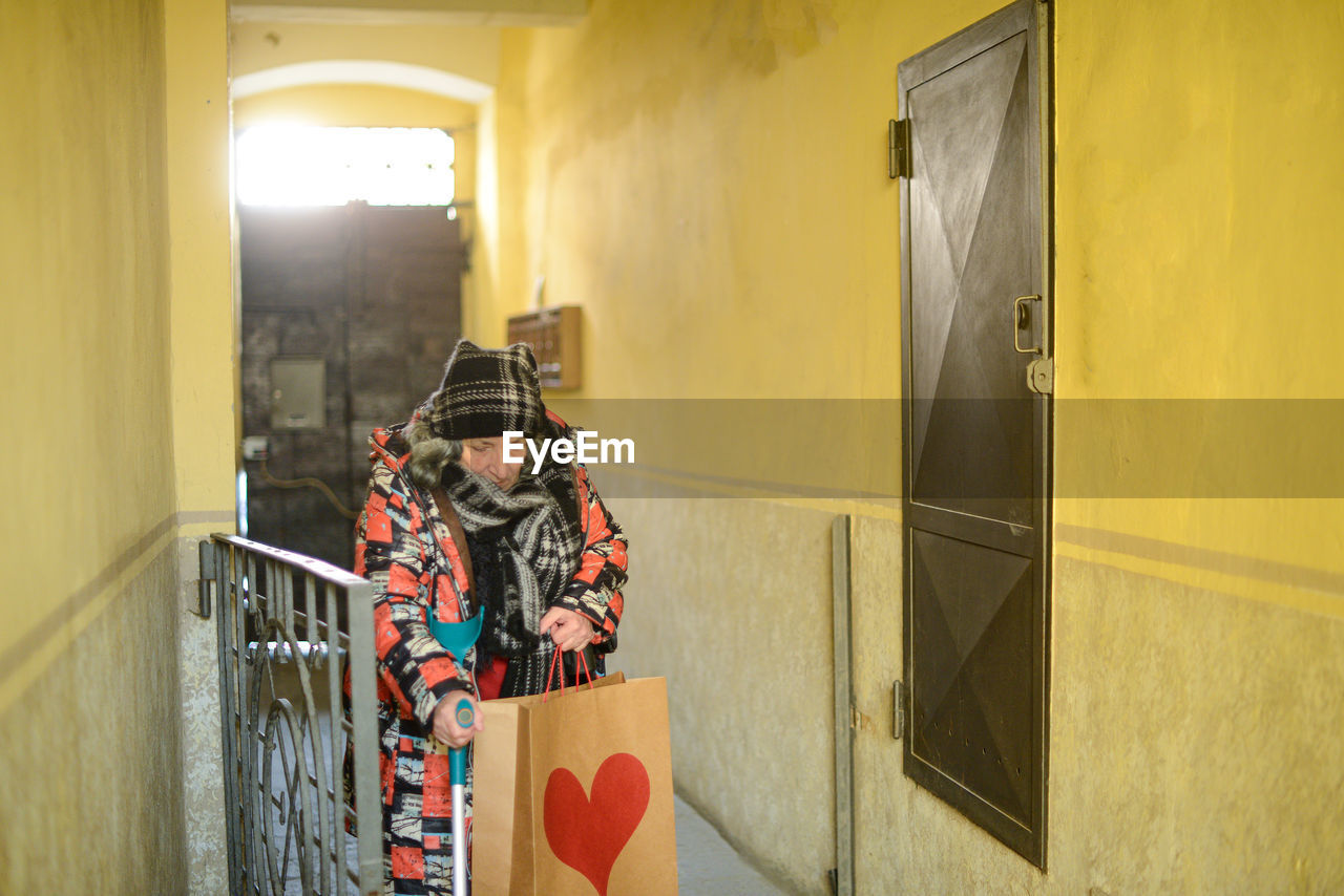 Senior east european disabled woman entering a building 