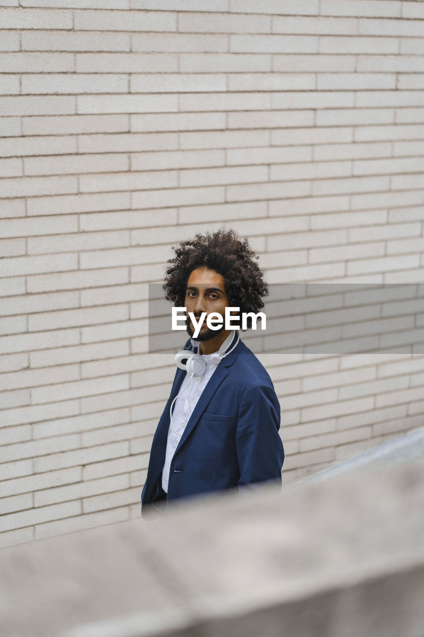 Male entrepreneur staring while standing by brick wall