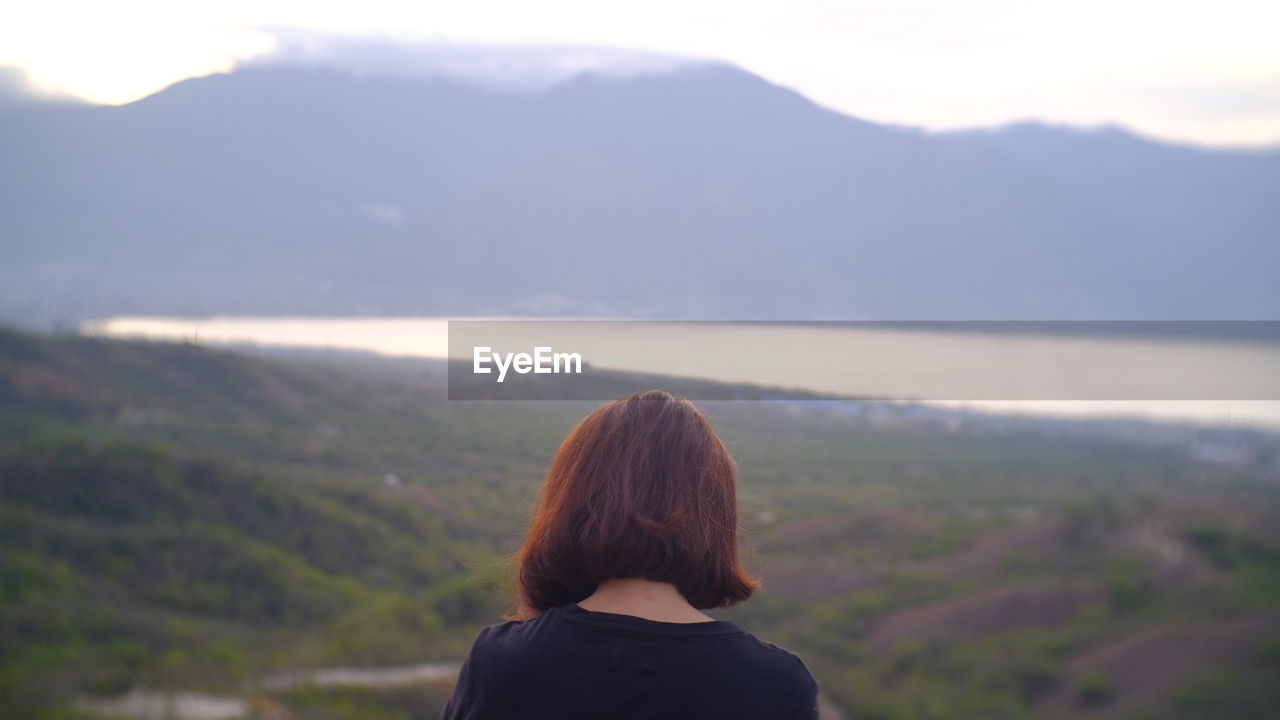 REAR VIEW OF WOMAN LOOKING AT MOUNTAIN