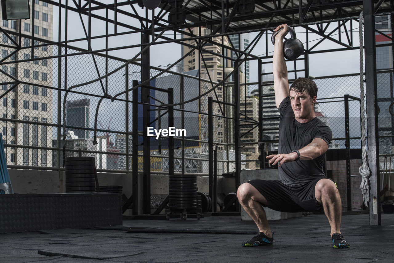 Man training with kettle bell at rooftop gym in bangkok