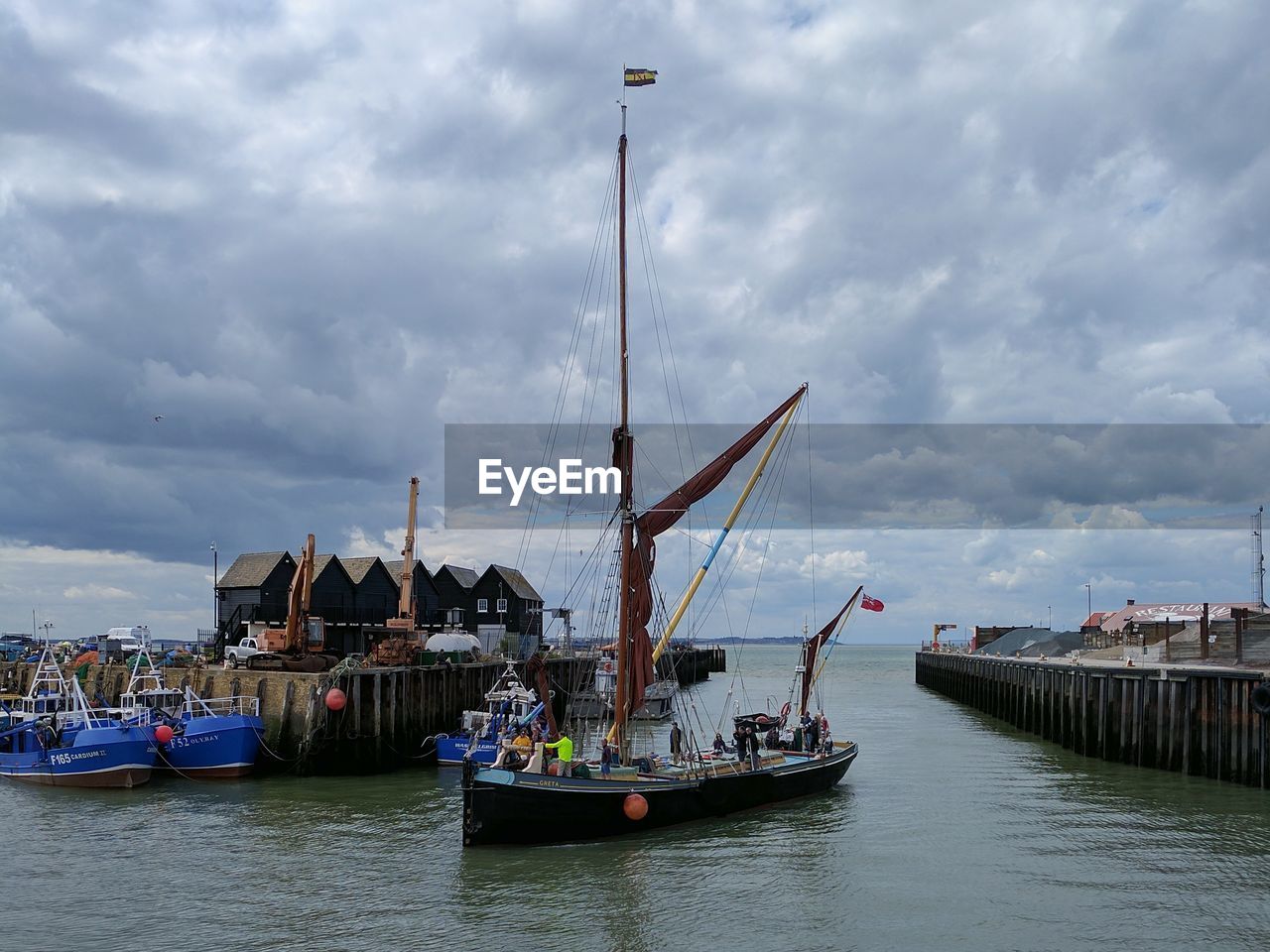 BOATS MOORED AT HARBOR AGAINST SKY