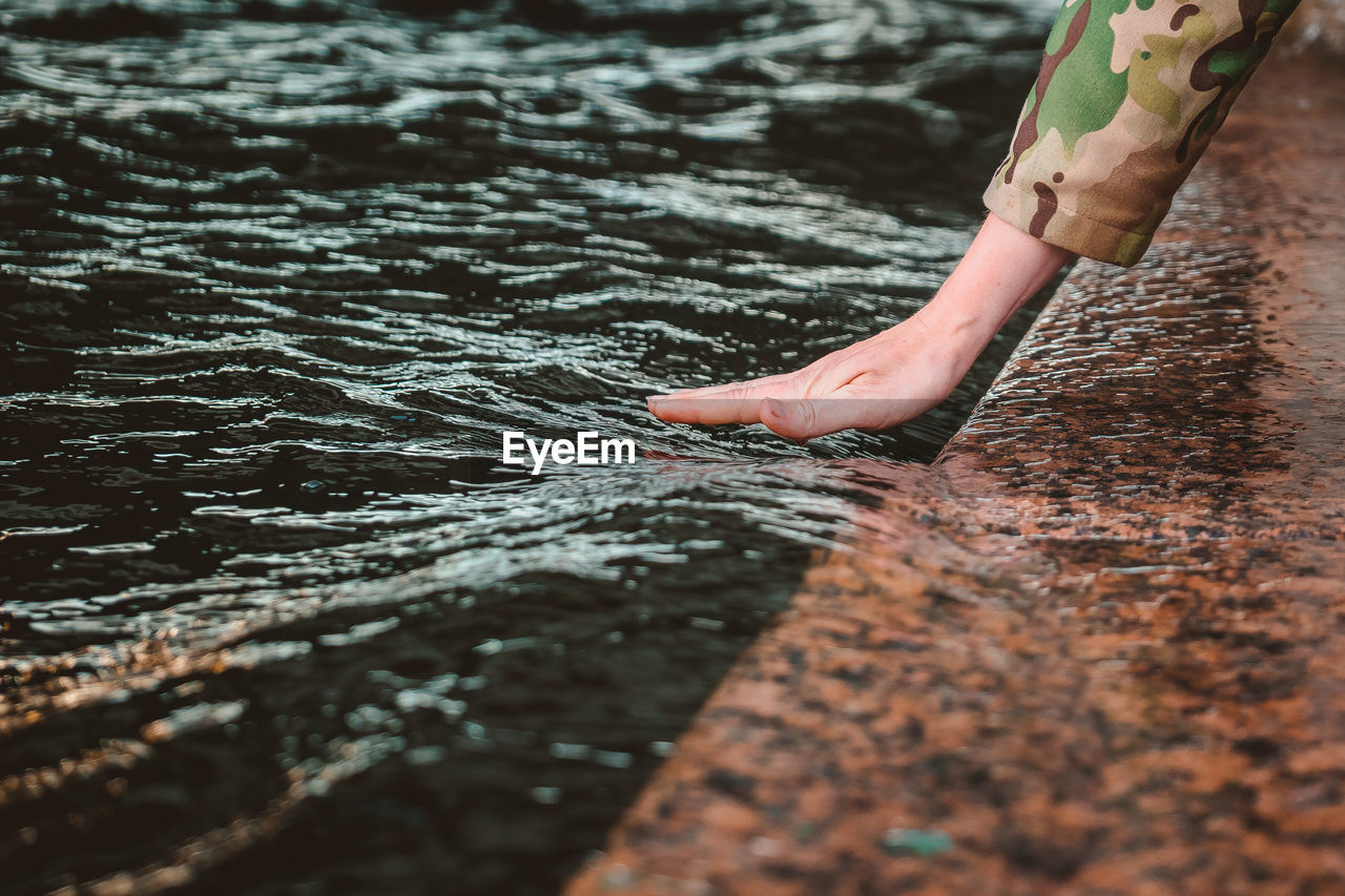 The girl's wet hand is stroking the wave. touching the river with the palm of your hand