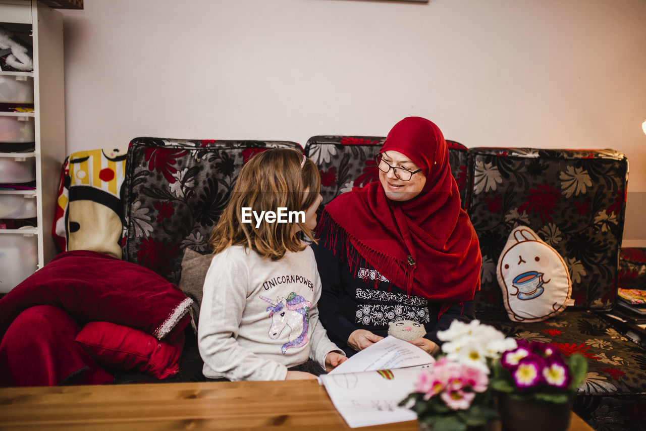 Mother with daughter sitting on sofa