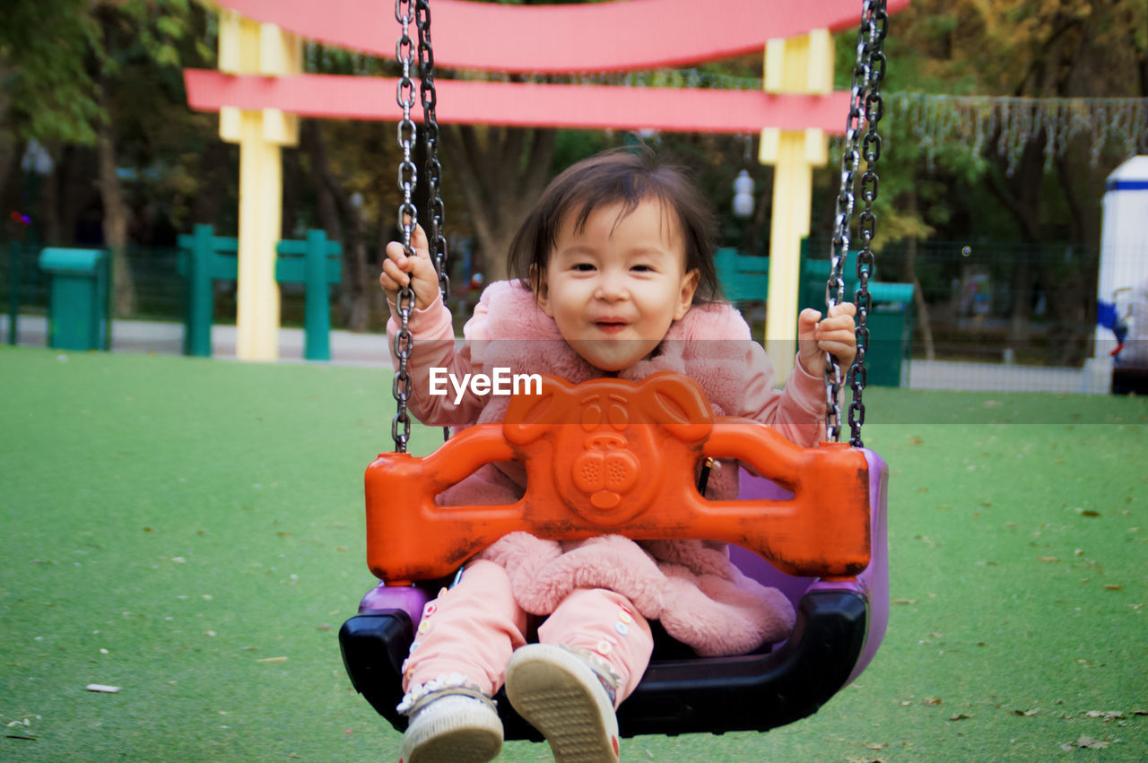Portrait of cute girl swinging at playground