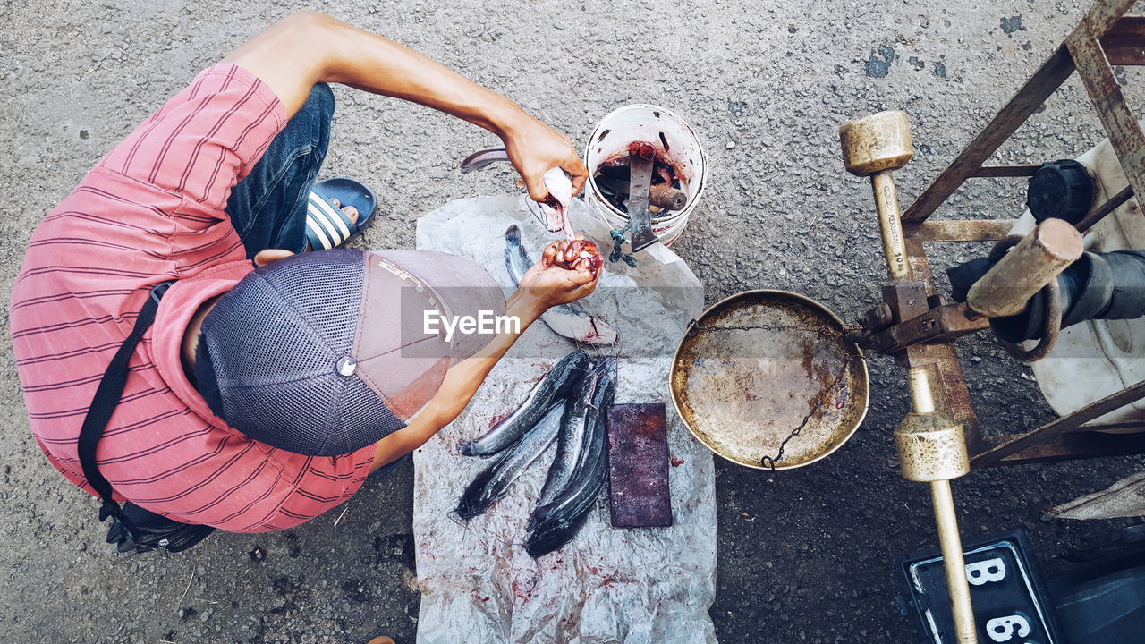 Directly above shot of man cutting fish on street