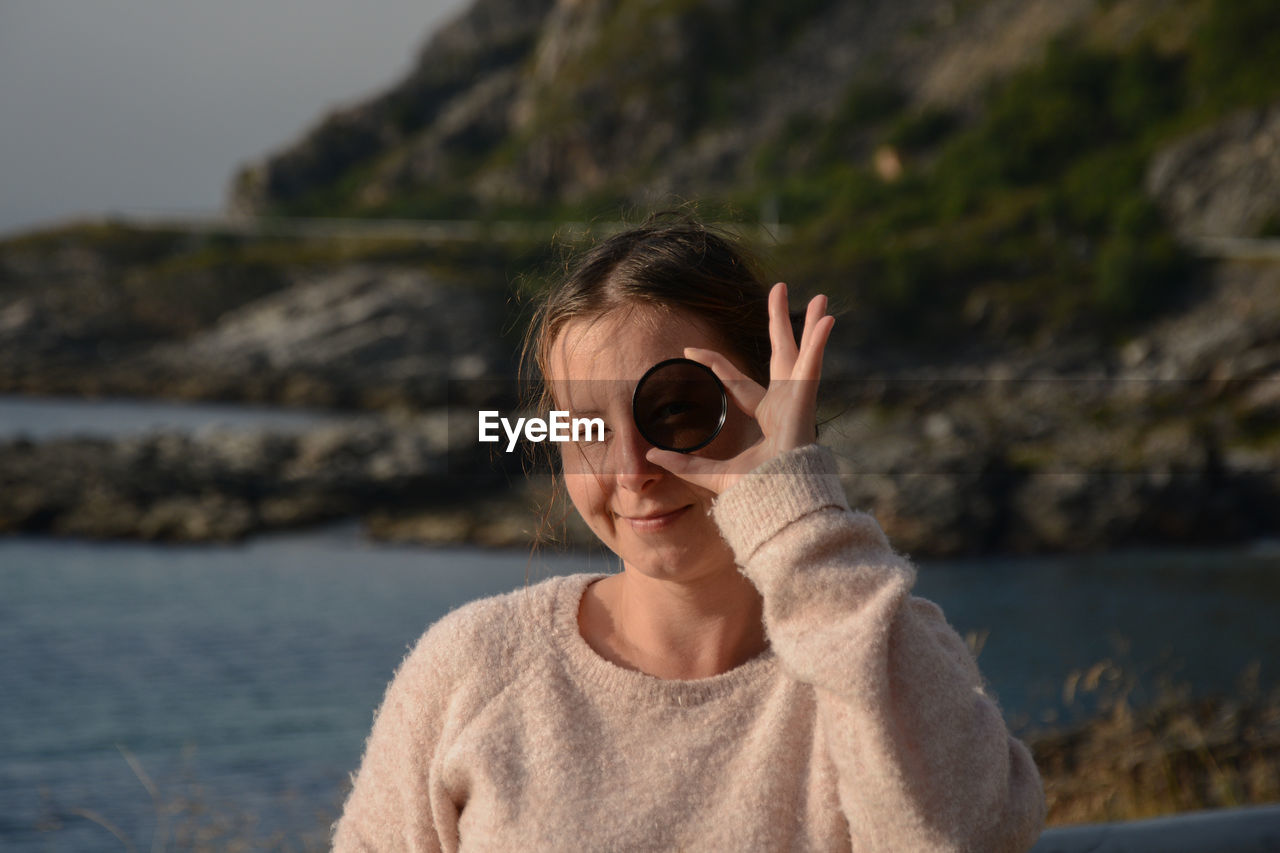 Portrait of woman looking through glass at beach