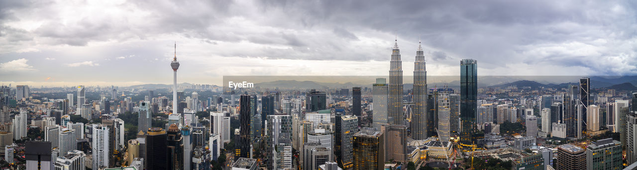 Panoramic view of city buildings against cloudy sky