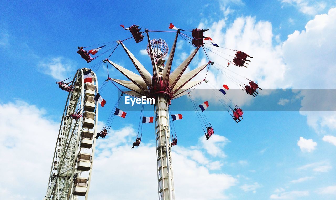 Low angle view of rides against cloudy sky in tuileries garden