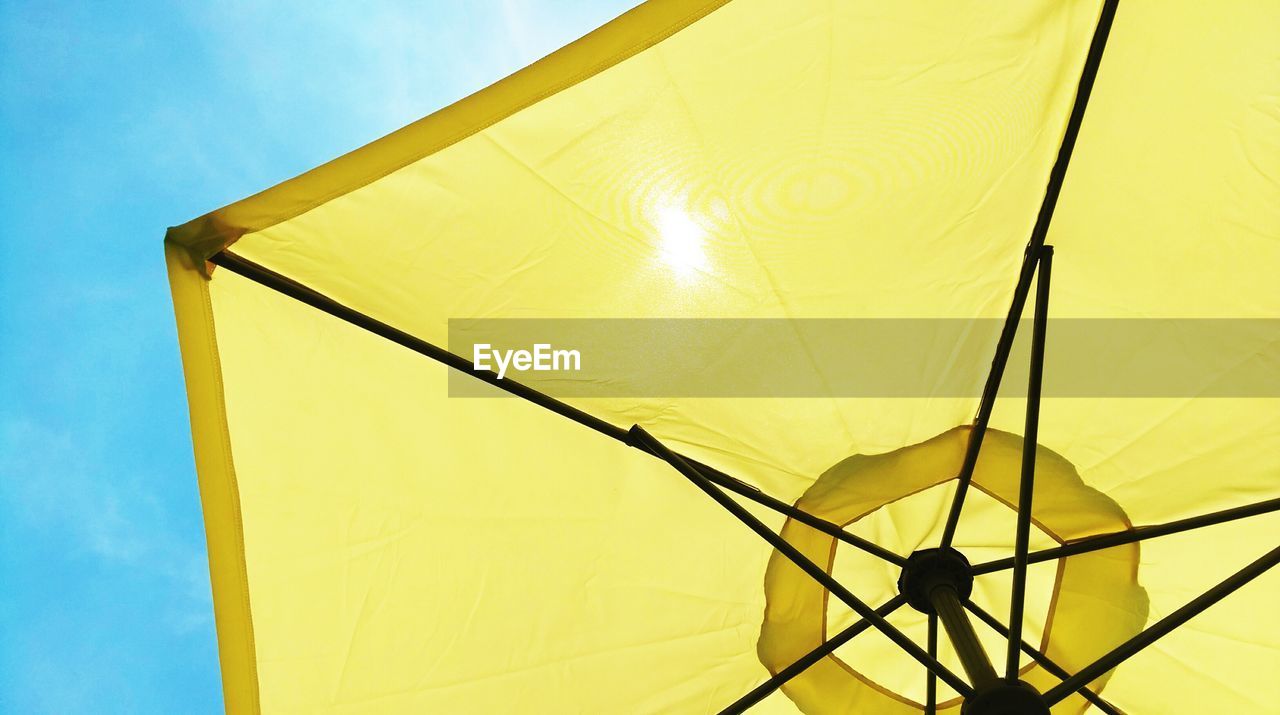 Low angle view of yellow parasol against sky at beach