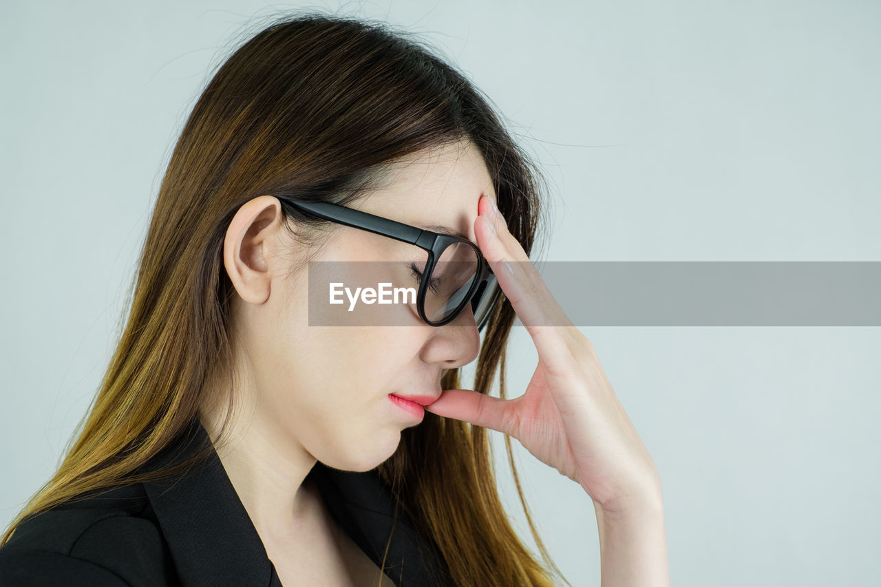Businesswoman suffering from headache against white background