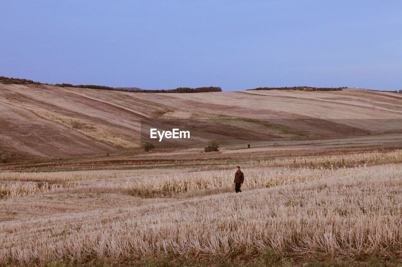 Mature woman standing on grassy field against clear sky