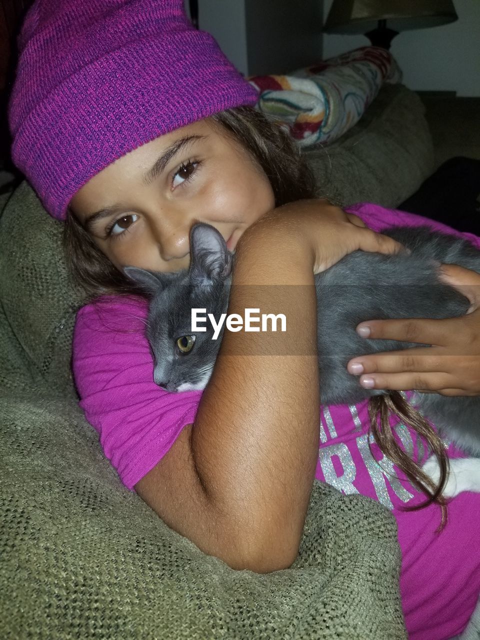 PORTRAIT OF YOUNG WOMAN WITH CAT ON PURPLE
