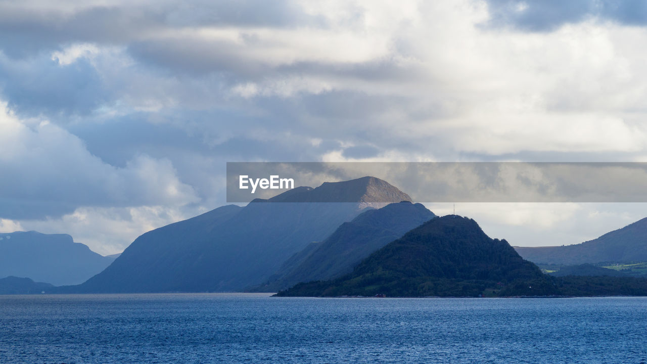 Scenic view of sea by mountains against sky