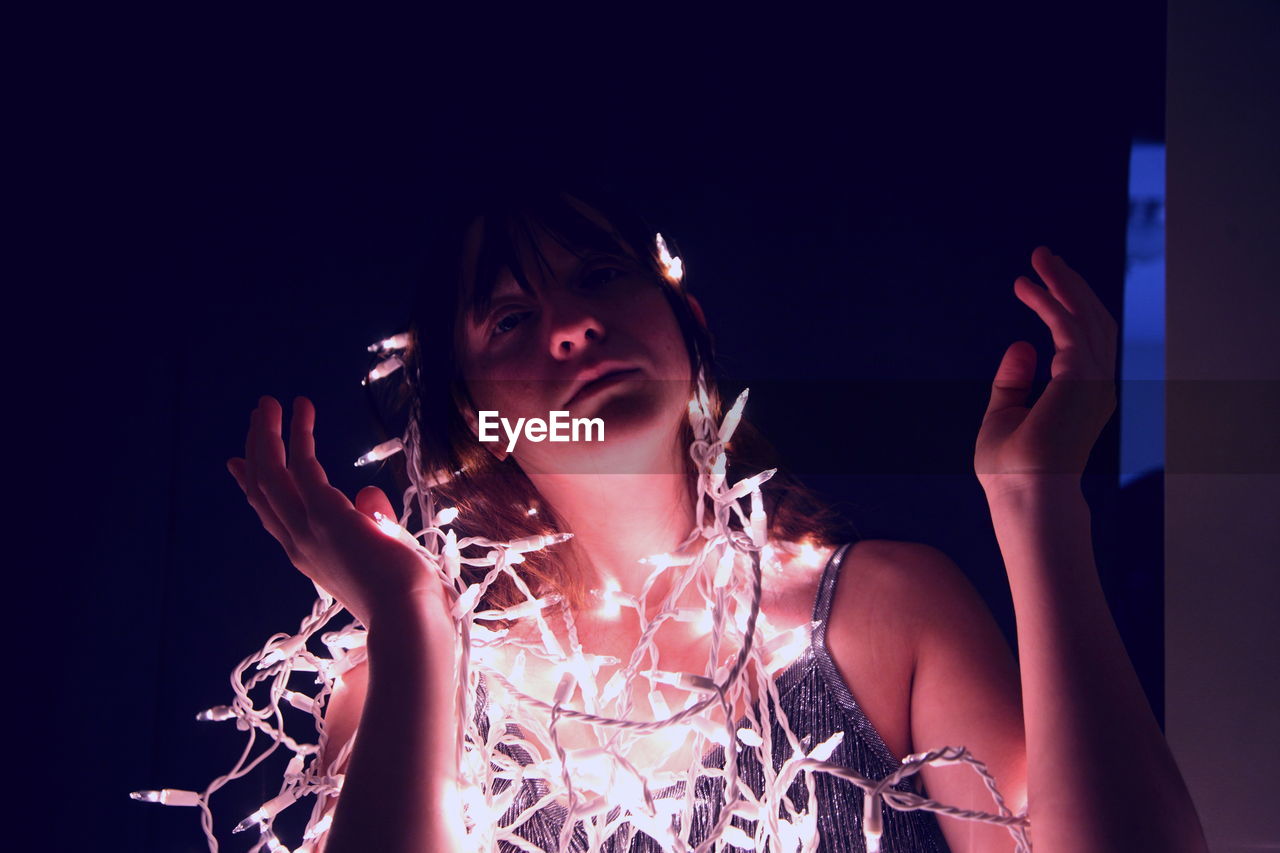 Teenage girl with illuminated string light in darkroom