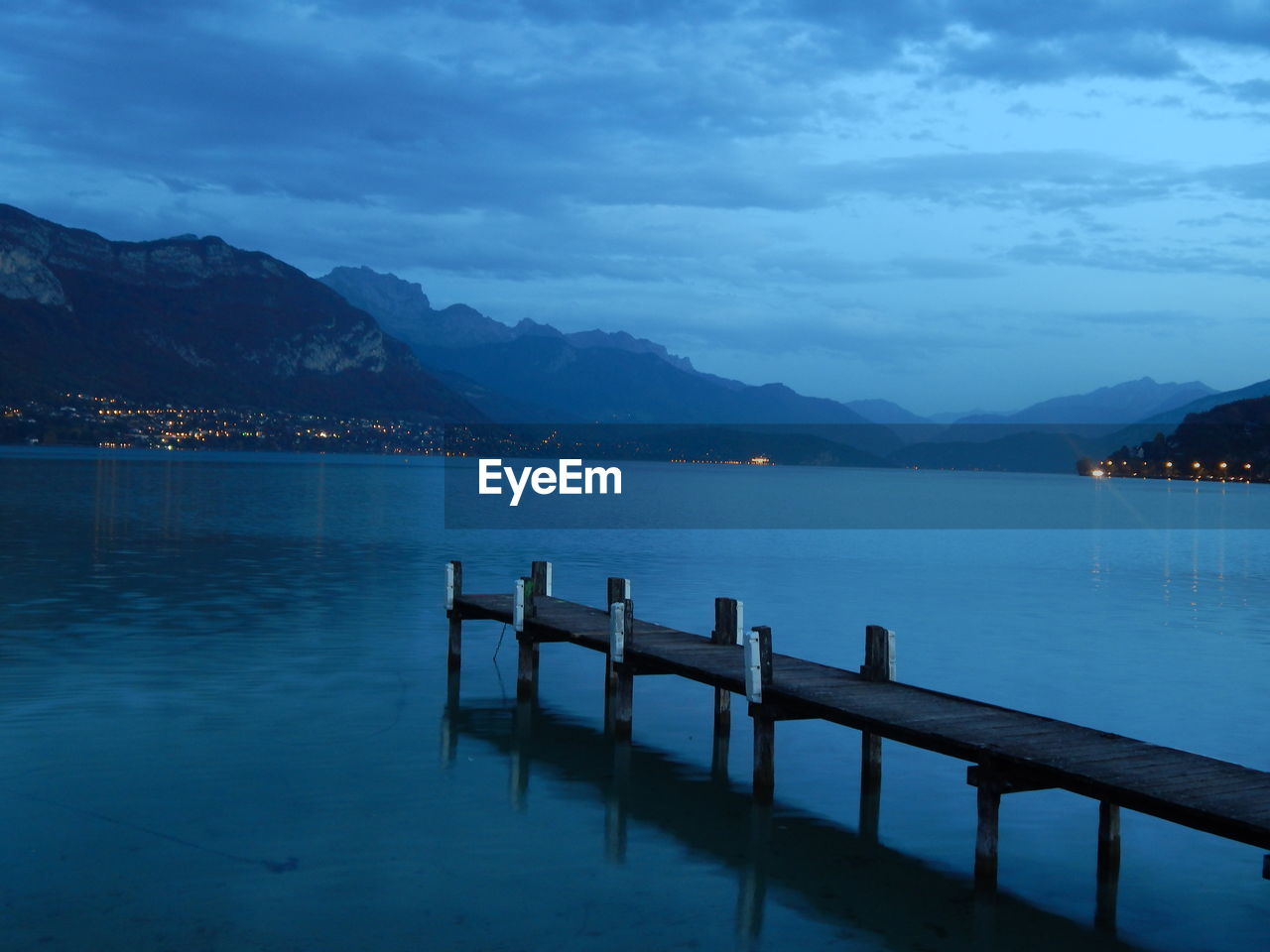 Pier on lake by town against sky