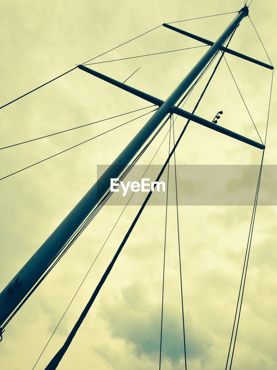 Low angle view of mast against cloudy sky