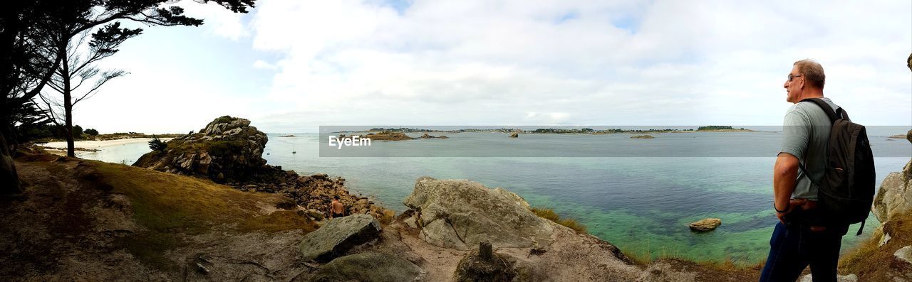 Man looking at sea while standing on shore against sky