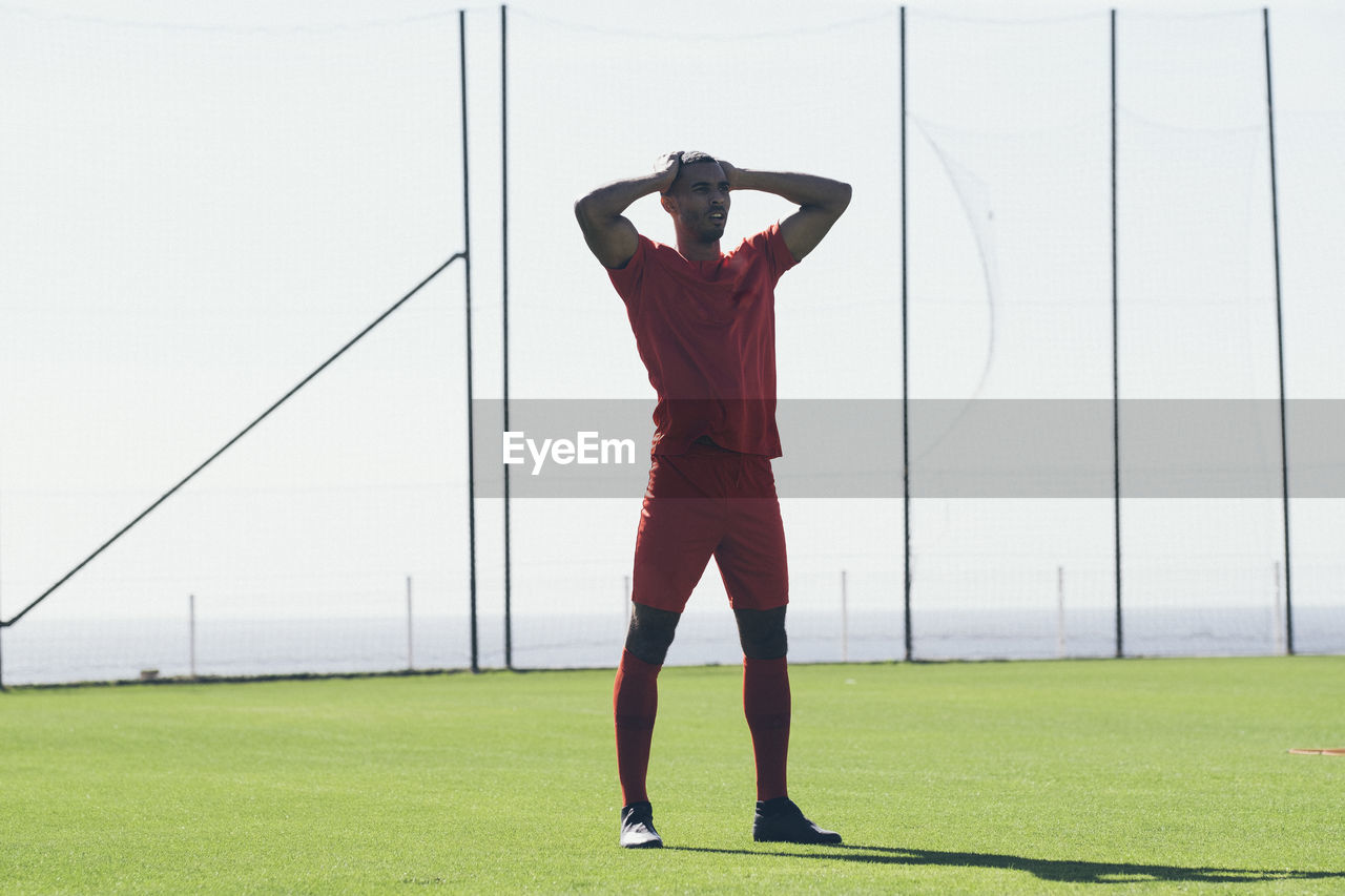 African american male soccer player standing on grass at pitch