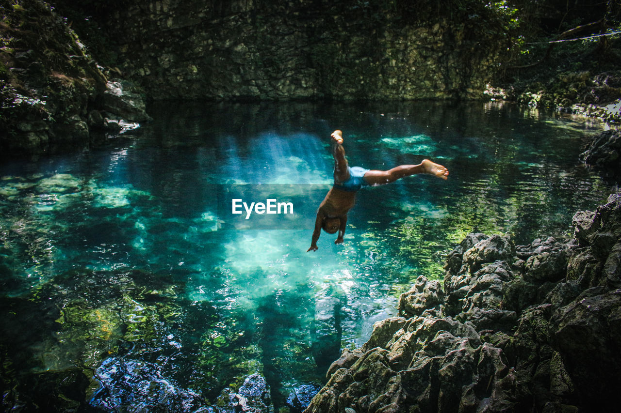 Full length of teenage boy jumping in pond