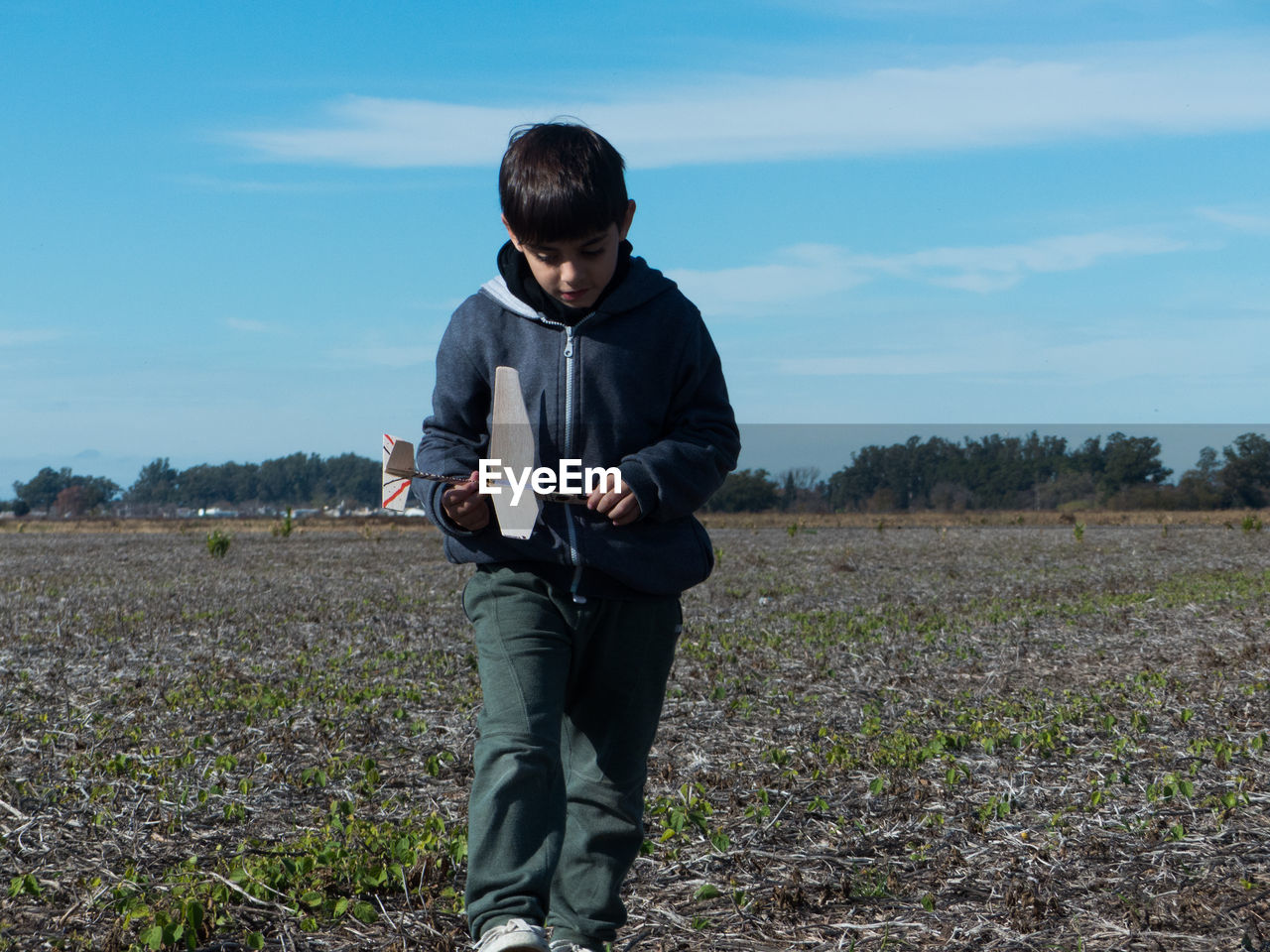 Boy with toy airplane walking on land