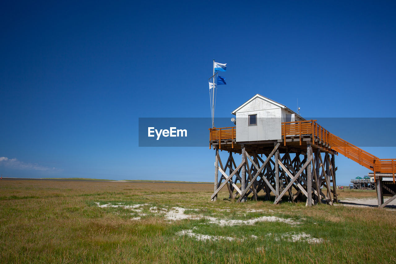 Built structure on field against clear blue sky