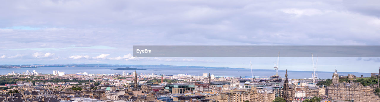 HIGH ANGLE SHOT OF TOWNSCAPE BY SEA AGAINST SKY