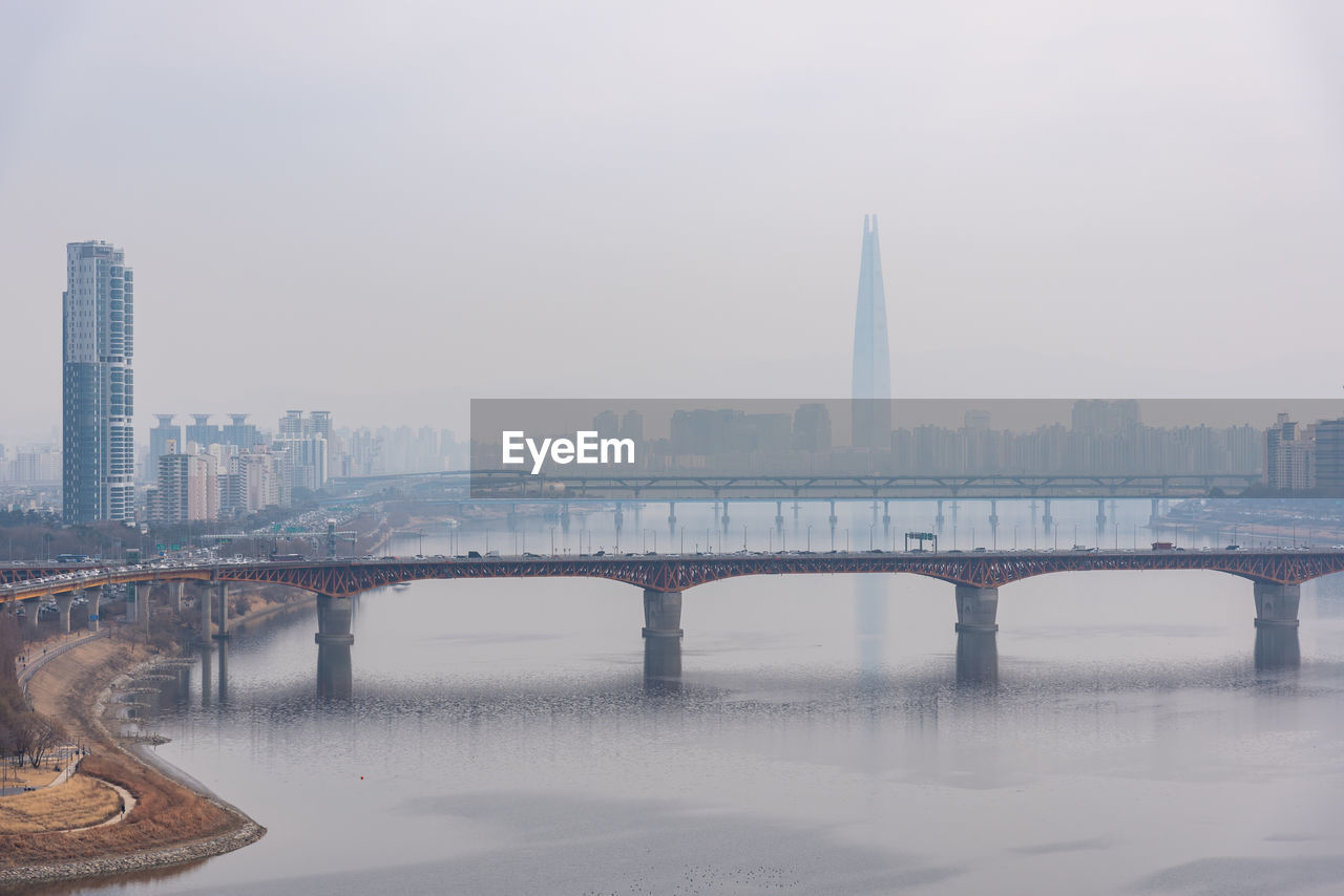 bridge over river in city against sky