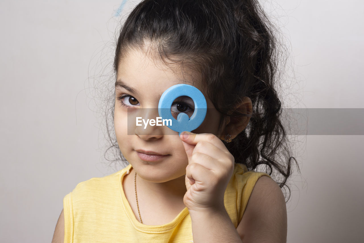 Little girl portrait peeking through english q letter q