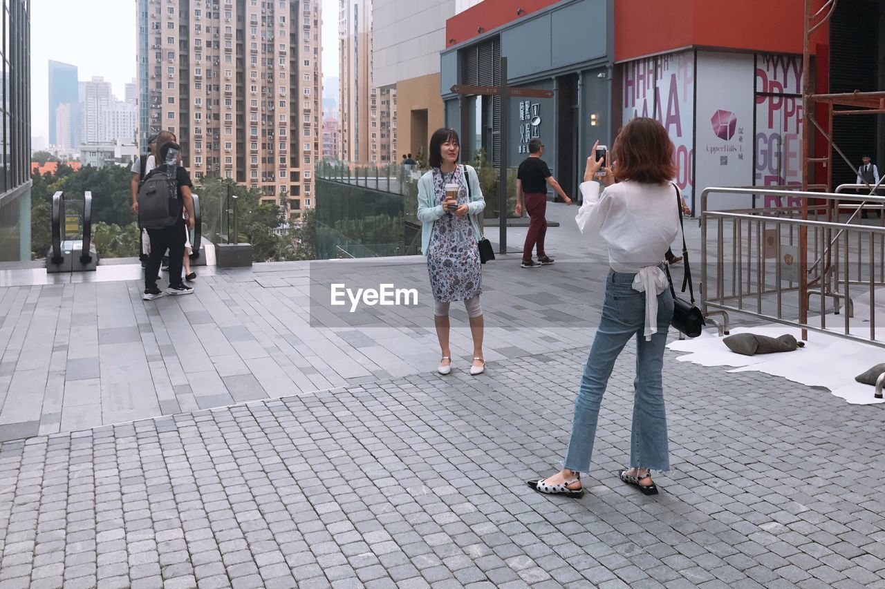 REAR VIEW OF PEOPLE WALKING ON STREET IN CITY